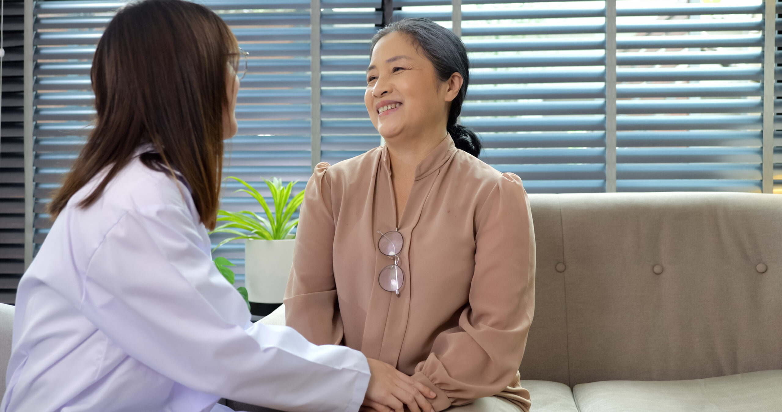 Smiling young female doctor enjoying conversation with happy senior woman
